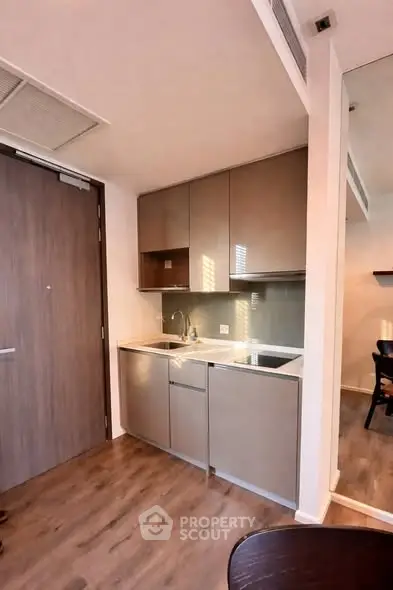 Modern compact kitchen with sleek cabinetry and integrated appliances in a stylish apartment.