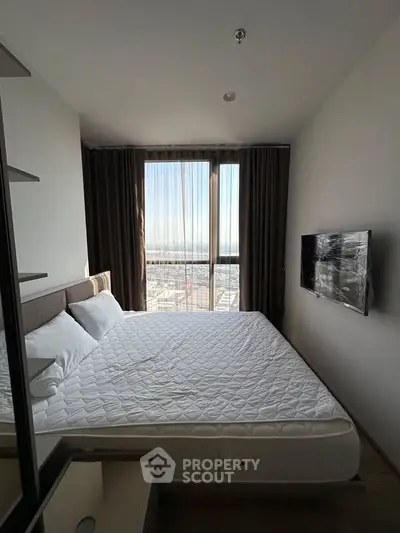 Modern bedroom with large window and city view, featuring a wall-mounted TV and cozy bed.