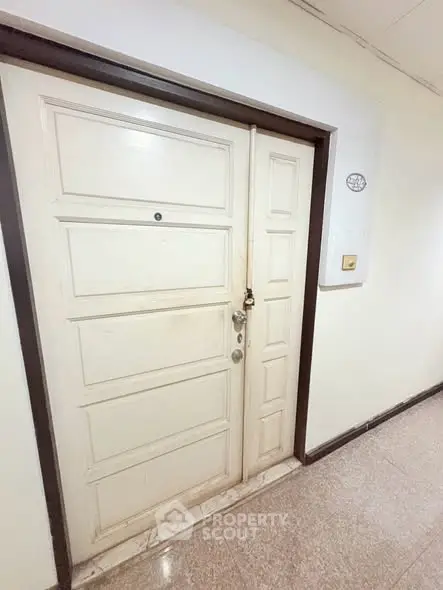 Sturdy white apartment door with secure lock in a well-maintained hallway.