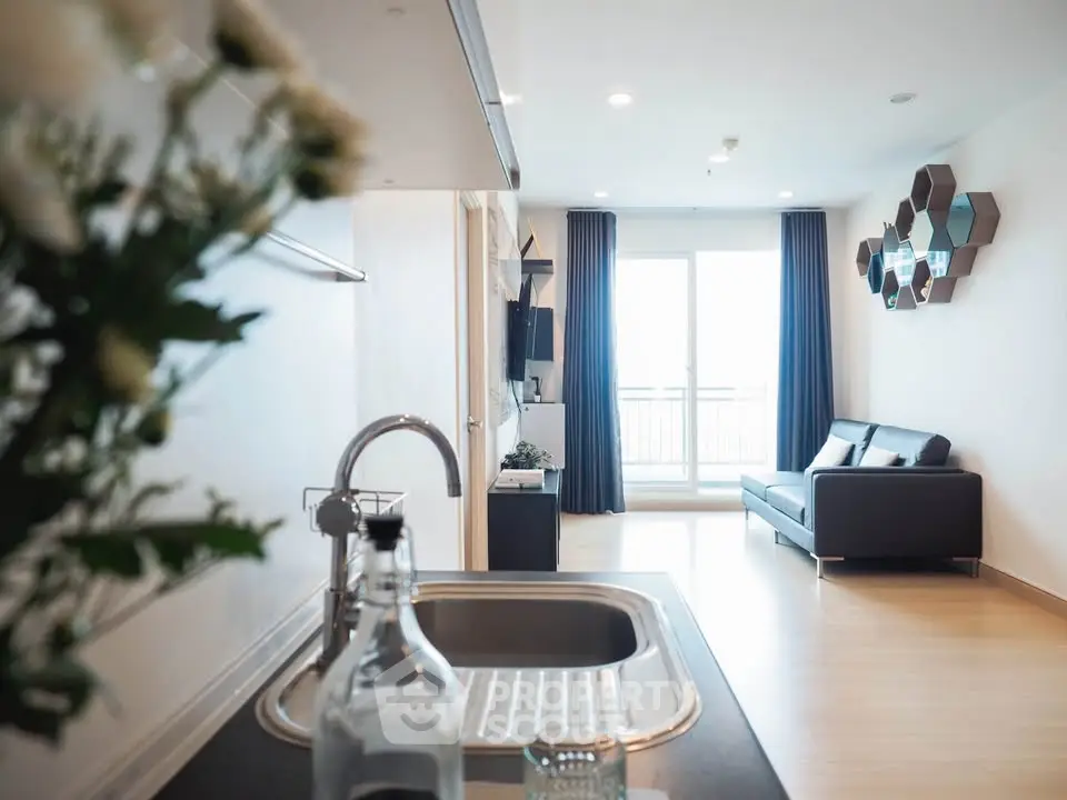 Modern open-plan living room with sleek kitchen and balcony view.