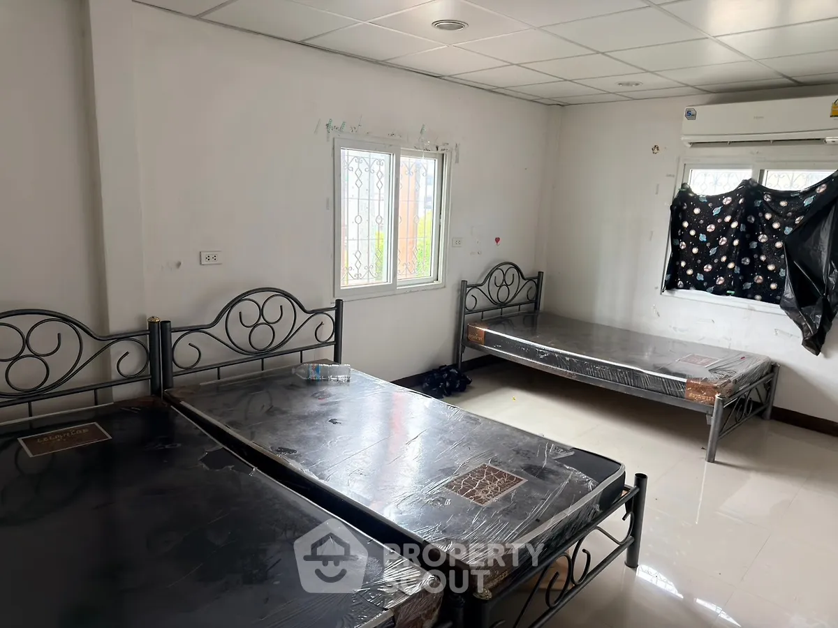 Spacious bedroom with twin beds and natural light, ideal for comfortable living.