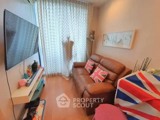 Cozy living room with leather sofa and wall-mounted TV, featuring British-themed decor.