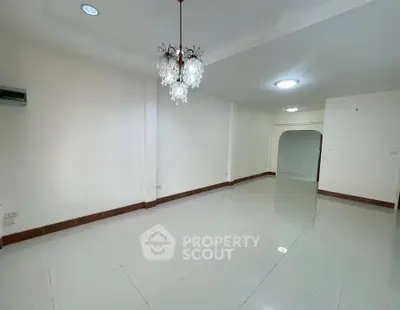 Spacious empty room with elegant chandelier and glossy white tiles
