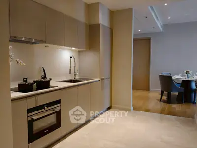 Modern kitchen with sleek cabinetry and dining area in luxury apartment.