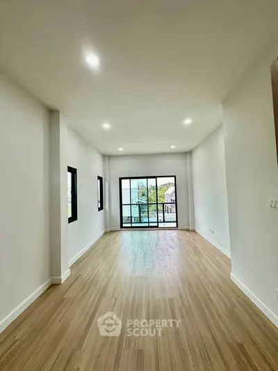 Spacious empty living room with large windows and wooden flooring