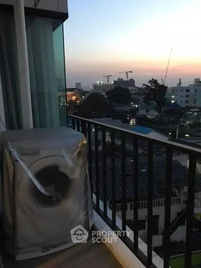 City view balcony with washing machine at sunset, perfect for urban living.