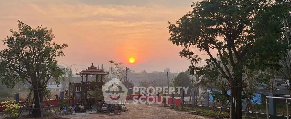 Stunning sunset view from a serene garden with lush trees and a charming gazebo.
