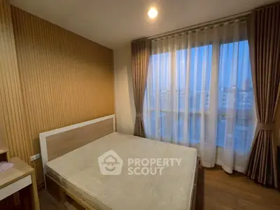 Cozy bedroom with large window offering city view and natural light