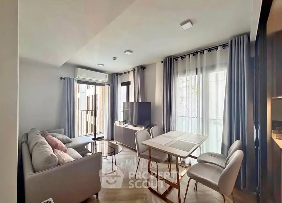 Modern living room with stylish furniture and natural light, featuring a cozy sofa and dining area.