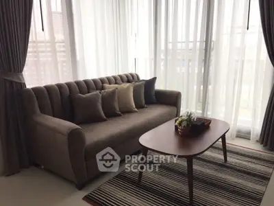 Stylish living room with elegant sofa and coffee table near large windows.