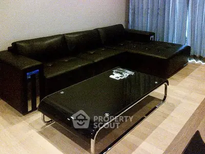 Modern living room with sleek black leather sofa and glass coffee table, perfect for stylish urban living.