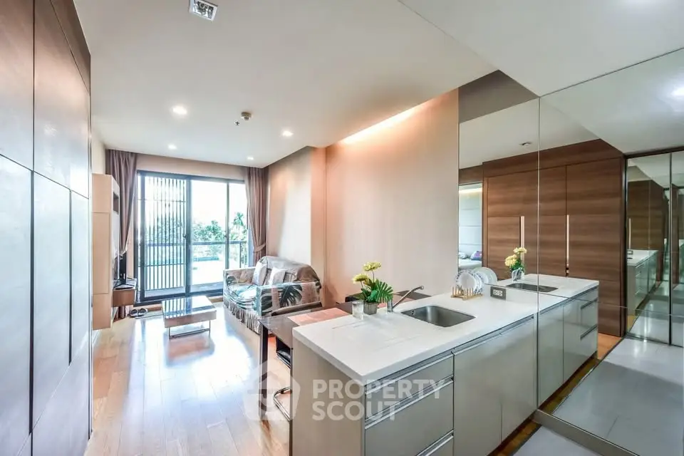 Modern open-layout living room with sleek kitchen and large windows offering natural light.