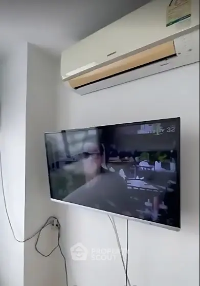 Modern living room with wall-mounted TV and air conditioning unit, showcasing sleek interior design.
