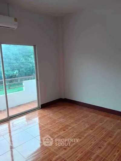 Spacious empty room with wooden flooring and balcony access