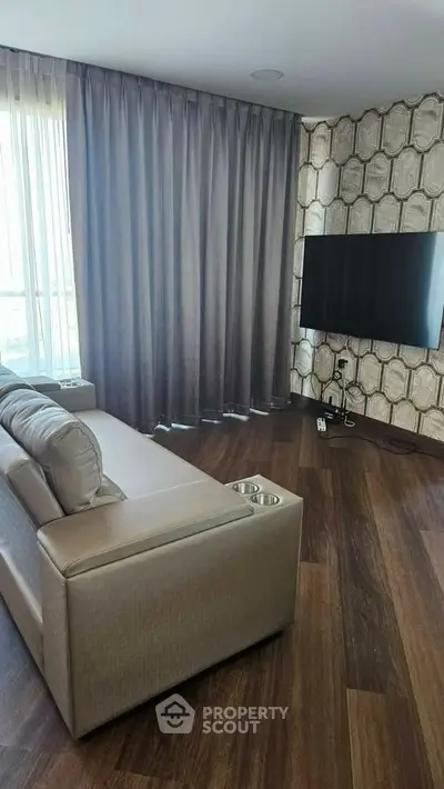 Modern living room with stylish decor, large TV, and elegant curtains.
