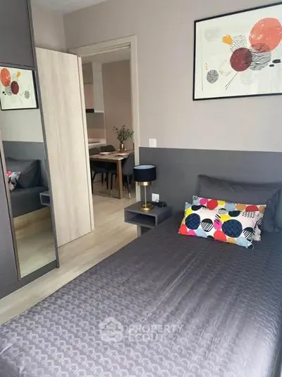 Modern bedroom with stylish decor and view into dining area, featuring colorful pillows and sleek furniture.