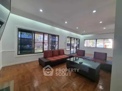 Spacious living room with modern furniture and large windows offering garden views.
