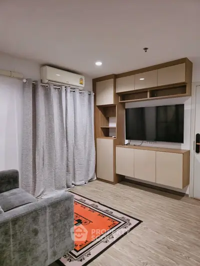 Modern living room with sleek cabinetry and wall-mounted TV, featuring cozy gray sofa and stylish decor.