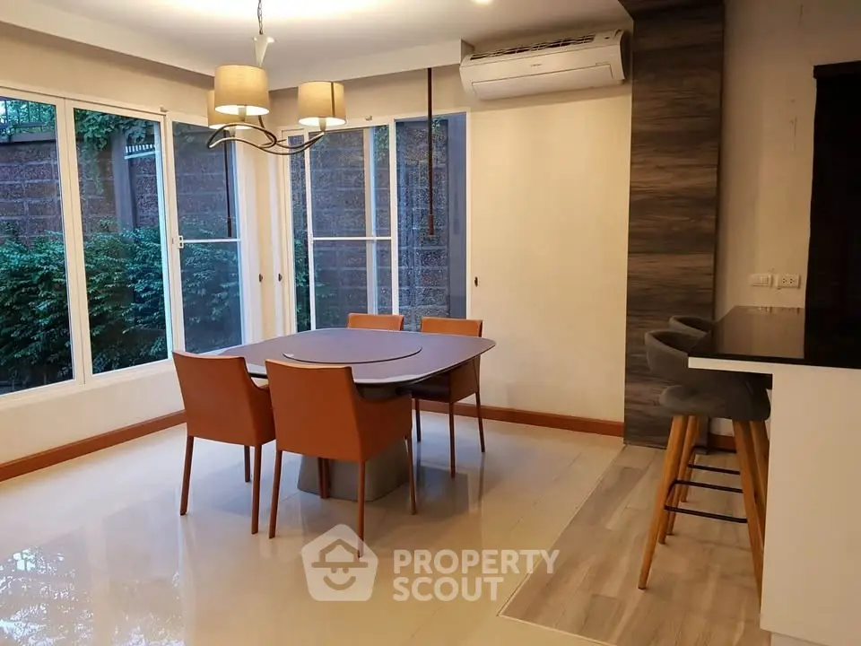 Elegant dining area with modern furniture and large windows in a stylish home.