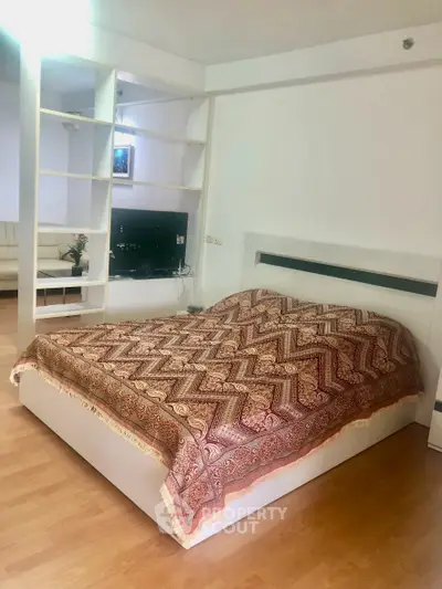 Spacious bedroom with elegant decor and open layout, featuring a cozy bed and stylish shelving.