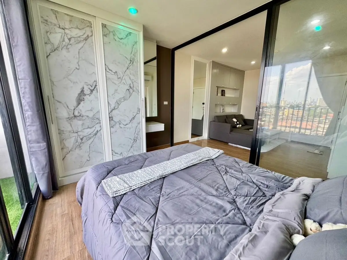 Modern bedroom with large windows and city view, featuring stylish decor and ample natural light.