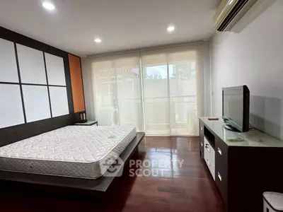 Spacious bedroom with modern decor and large windows leading to a balcony.
