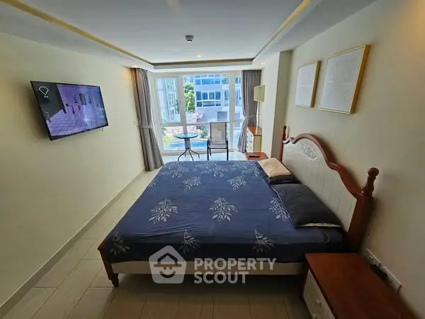 Spacious bedroom with balcony and modern decor, featuring a comfortable bed and wall-mounted TV.
