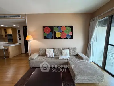 Modern living room with stylish decor and open kitchen layout, featuring a cozy sofa and vibrant wall art.