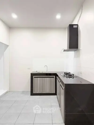 Modern kitchen with sleek black countertops and gas stove in a minimalist design.