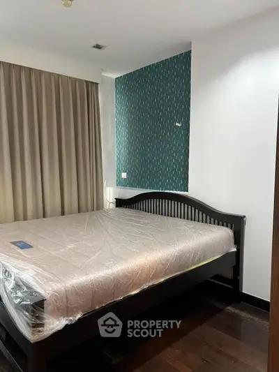 Spacious bedroom with elegant dark wood flooring and stylish accent wall.