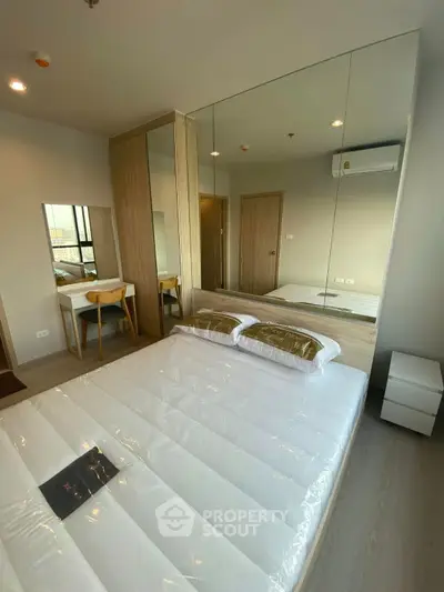 Modern bedroom with mirrored wall and sleek furnishings in a stylish apartment.