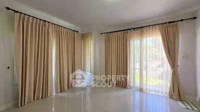 Spacious room with elegant floor-to-ceiling curtains and large windows for natural light.
