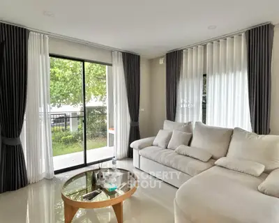 Spacious living room with modern decor and garden view, featuring plush white sofa and elegant curtains.