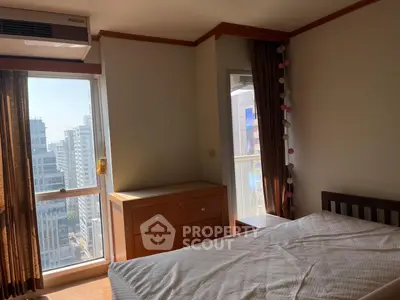 Cozy bedroom with city view, featuring wooden furniture and large windows for natural light.