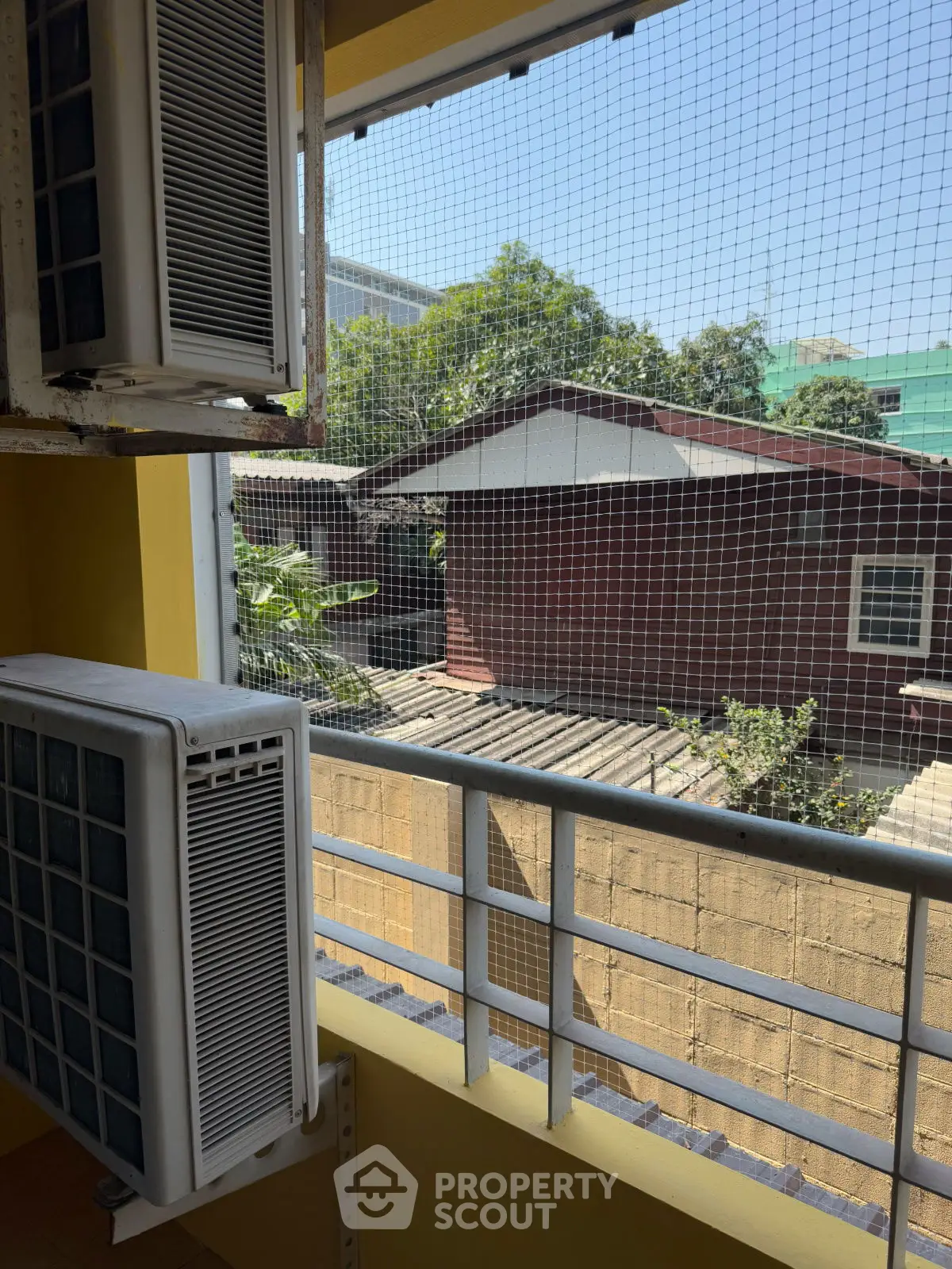 Urban balcony view with air conditioning units and neighboring houses.