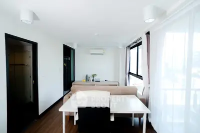 Modern living room with dining area and large windows offering natural light