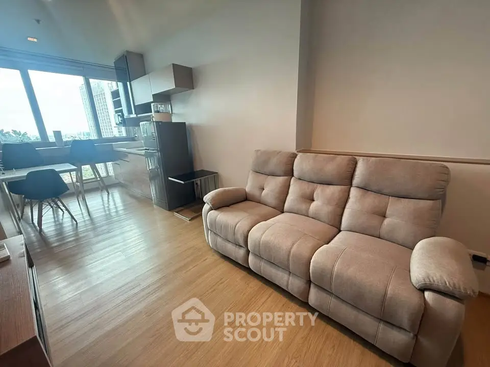 Modern living room with cozy sofa and dining area, featuring large windows and natural light.