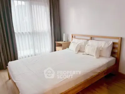 Bright and cozy bedroom with wooden bed frame and large window in modern apartment.