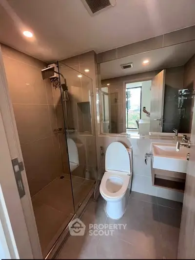 Modern bathroom with glass shower and sleek fixtures in contemporary apartment.