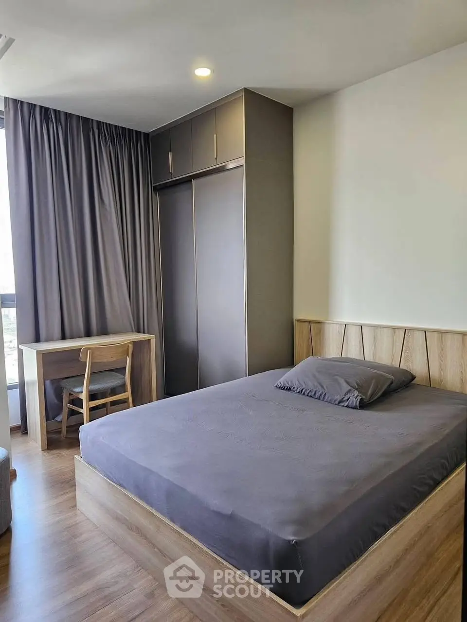 Modern bedroom with sleek furniture and large window for natural light.