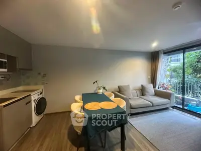 Modern living room with cozy sofa, dining area, and washing machine near balcony view.