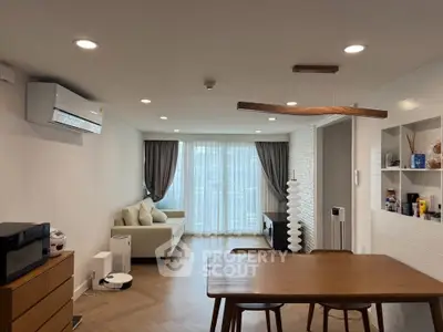 Modern living room with elegant decor and natural light, featuring a cozy sofa and stylish dining area.