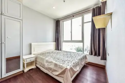 Bright and airy bedroom with large window and elegant furnishings in modern apartment.
