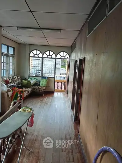 Charming hallway with wooden flooring and arched windows, offering a cozy and inviting atmosphere.