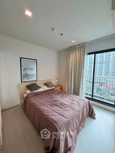 Modern bedroom with large window and city view, featuring cozy bedding and stylish decor.