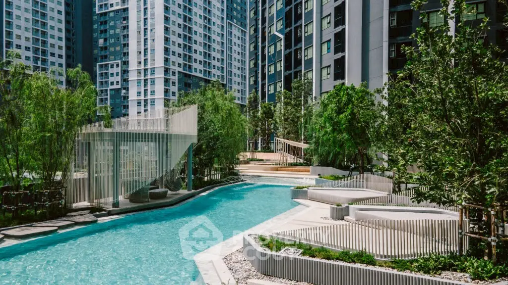 Luxurious modern apartment complex with stunning pool and lush greenery.