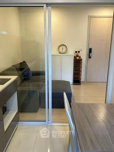 Modern apartment interior with glass partition, cozy living area, and stylish dining table.