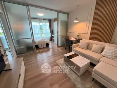 Modern living room with stylish decor and sliding glass doors leading to a cozy bedroom.