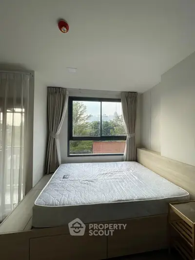 Bright bedroom with large window and modern decor, featuring a comfortable bed and serene outdoor view.