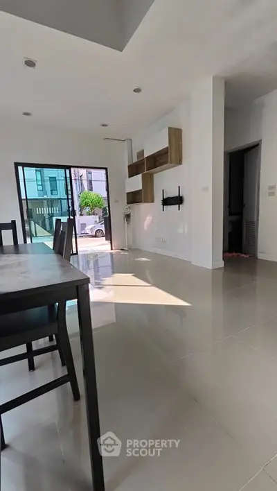 Spacious modern living room with sleek tile flooring and stylish wall shelves, perfect for contemporary living.